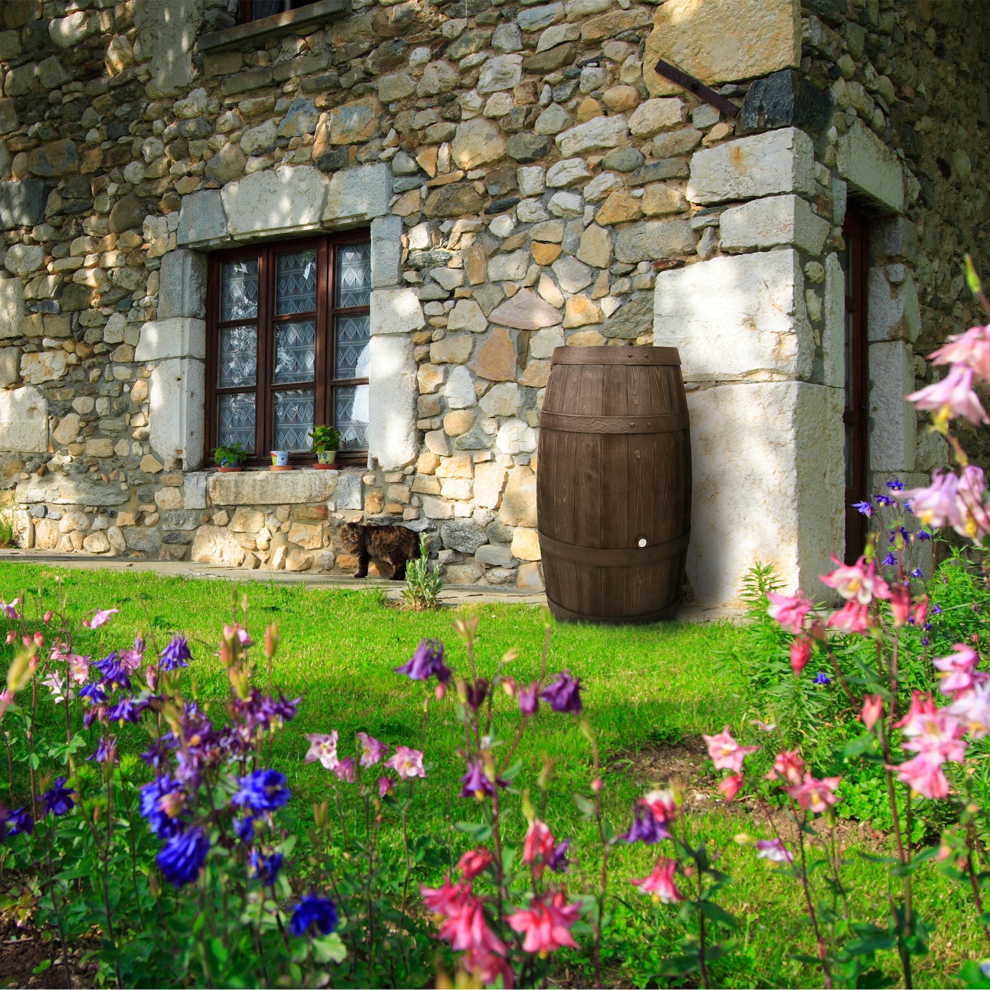 Rustikales Steinhaus mit einer YourCasa Regentonne 250 Liter [Holz] - Frostsicher & UV-beständig neben einem lebendigen Blumengarten.