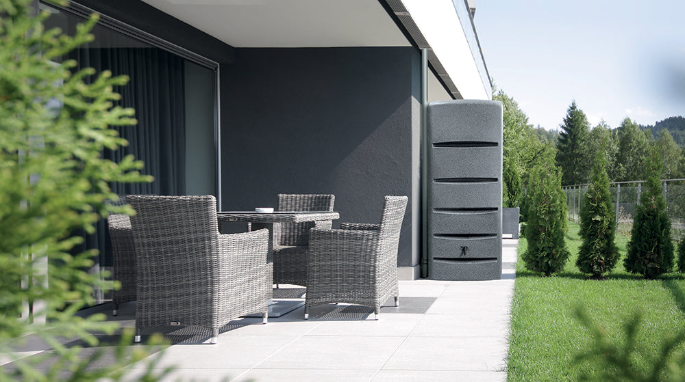 Moderne Terrasse mit Korbmöbeln mit Blick auf eine Wiese mit YourCasa Regentonne [EcoTower] – Platzsparend und Stilvoll – 260 und 720 Liter von yourcasa-de und Bäumen.