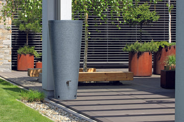 Ein großer Pflanzkübel auf einer Terrasse, gefüllt mit Tubo-Tank 320 Liter – Robuste Regentonne mit großem Fassungsvermögen und stilvollem Design von yourcasa-de.