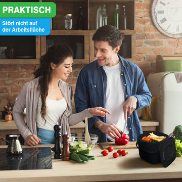 Ein Paar bereitet gemeinsam eine Mahlzeit in einer Küche zu und legt dabei Wert auf eine aufgeräumte Arbeitsplatte und ihren neuen Komposteimer für YourCasa® Biomülleimer Küche 4L – spülmaschinenfest & geruchsdicht von yourcasa-de.