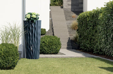 Bepflanzte Regentonne steht in einem Garten