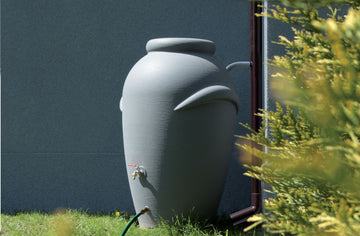 Regentonne vor Haus. Gartenpflege im Sommer.