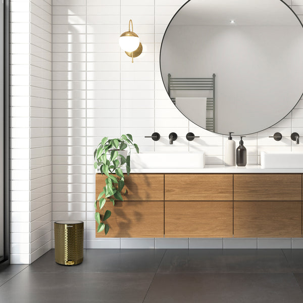 Modernes Badezimmer-Interieur mit wandmontiertem Waschtisch, rundem Spiegel, dekorativer Pflanze und einem YourCasa® Edelstahl Mülleimer Bad 5L – Pyramiden-Oberflächenstruktur von yourcasa-de.