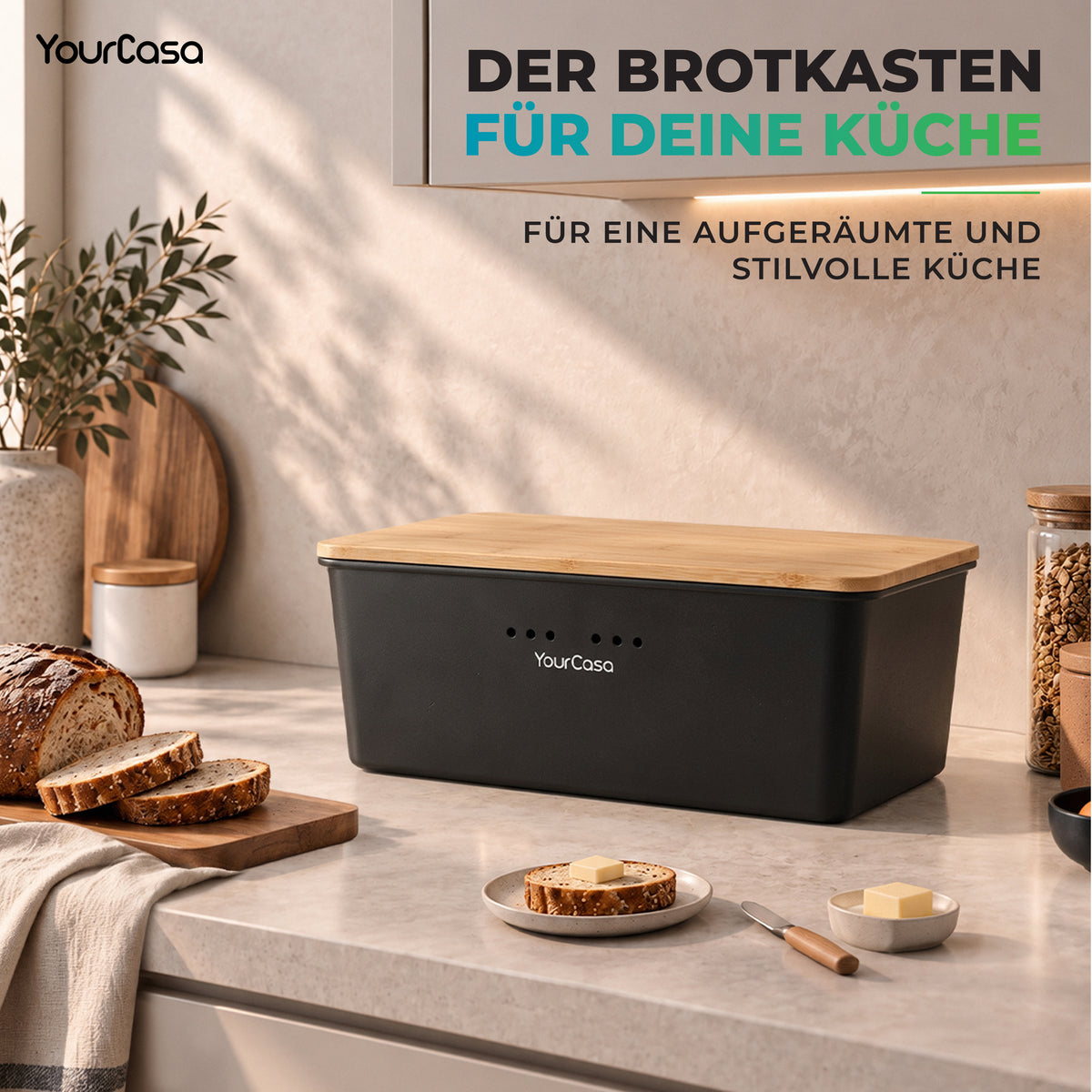 Schwarze Brotdose für die Küche auf heller Arbeitsplatte neben Butterbrot