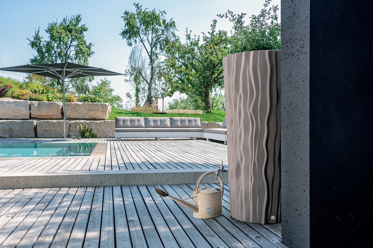 Moderne Außendusche auf einem Holzdeck neben einem Pool mit Liegebereich im Hintergrund, inklusive Regenwassernutzung aus einer YourCasa Regentonne 160 Liter [AquaDesign Flower] - Frostsicher & UV-beständig von yourcasa-de.