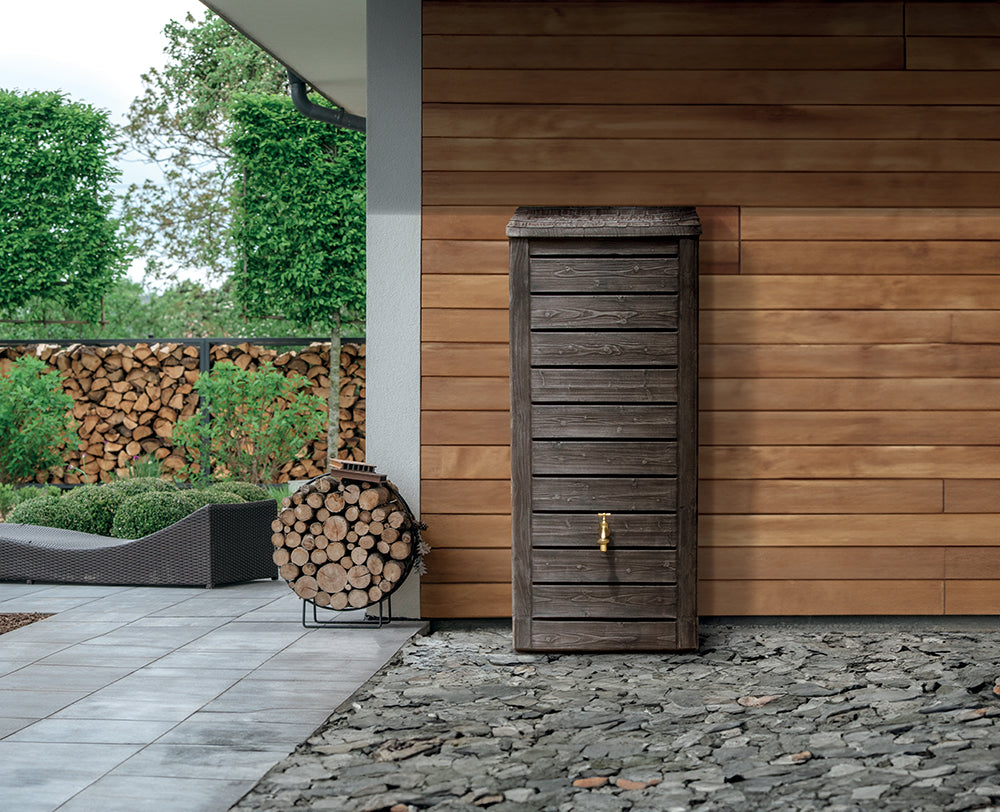 Moderner Außenbereich mit einem Holzlagerschrank und einem runden Holzregal vor einer Holzwand mit einer YourCasa Regentonne für nachhaltige Bewässerung.